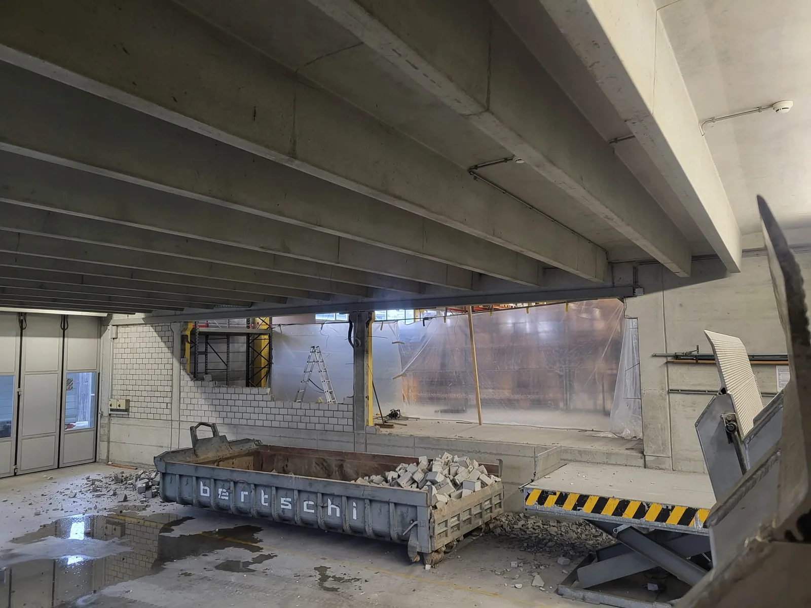 Rückbau in der Halle — volle Mulde mit Bauschutt und sichtbarer Materialtrennung